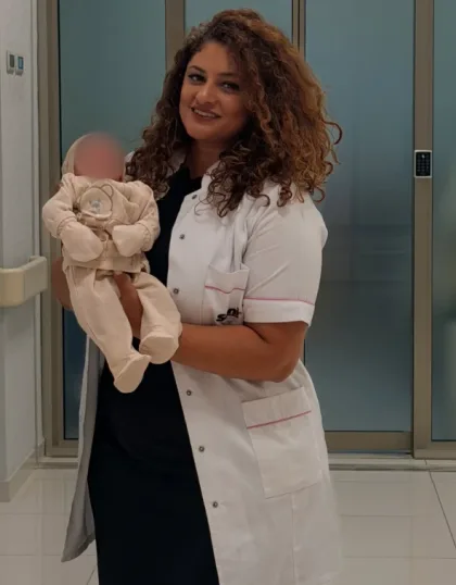 Dr. Fatimə Oruczadə hospital dəhlizində körpəni qucağında tutur